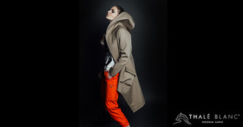 Woman wearing designer  coat with hood and orange pants from Thale Blanc trunk show.