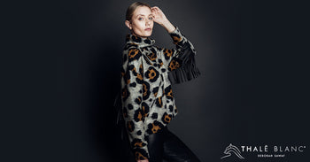 Woman wearing designer turtleneck with leopard print and black fringe on arms.