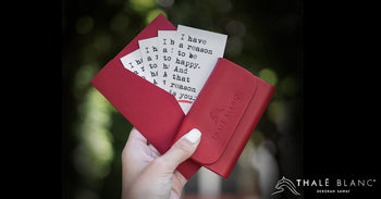 Red leather business card case containing happy cards.