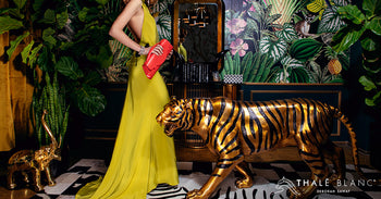 Woman wearing luxury yellow halter gown and carrying red embossed leather evening bag.