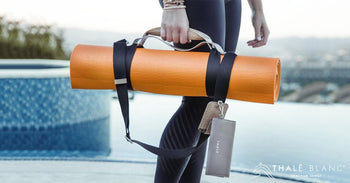 Yoga mat carrier strap made from vegan leather, holding orange yoga mat.