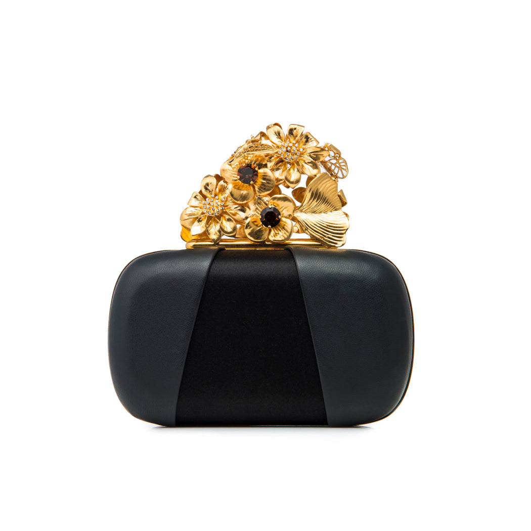 A show-stopping luxury evening handbag. Black satin and soft calf leather in black creates a cool contrast body that showcases the intricate gold-toned floral and butterfly closure. Amber and clear crystal embellishments complete the delicate details. A chain converts the handheld clutch into a wristlet.
