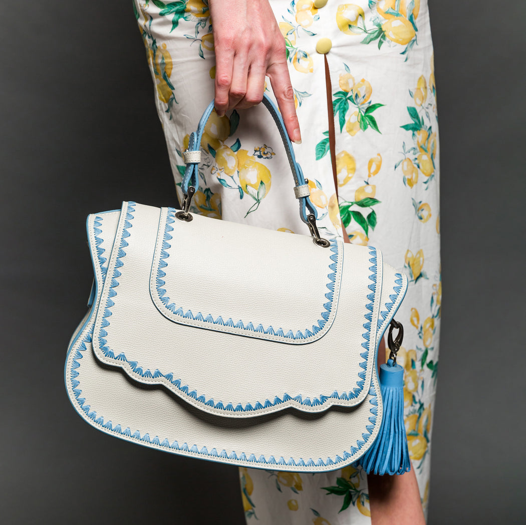 Woman holding white leather designer handbag