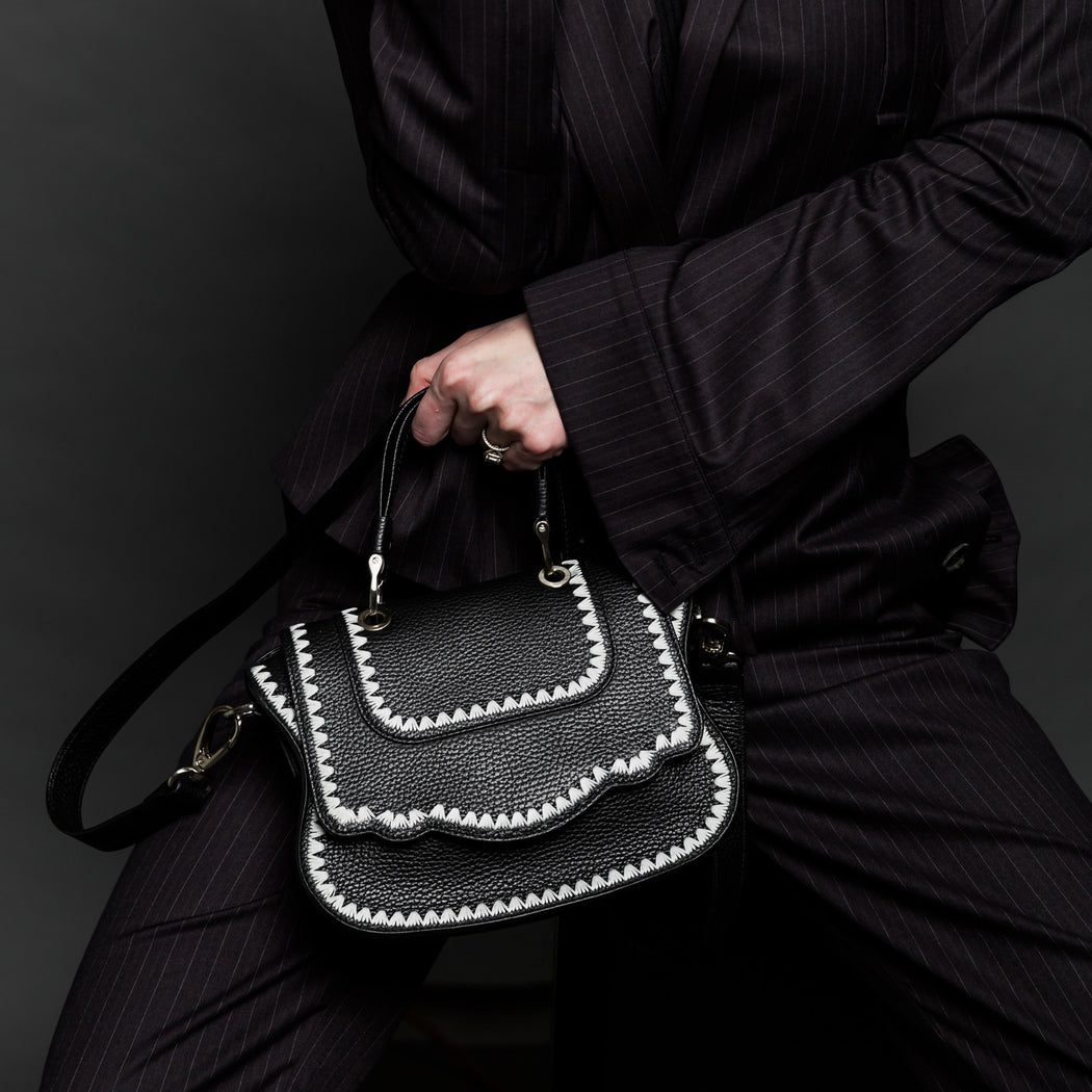 Woman holding black designer crossbody bag, mini.