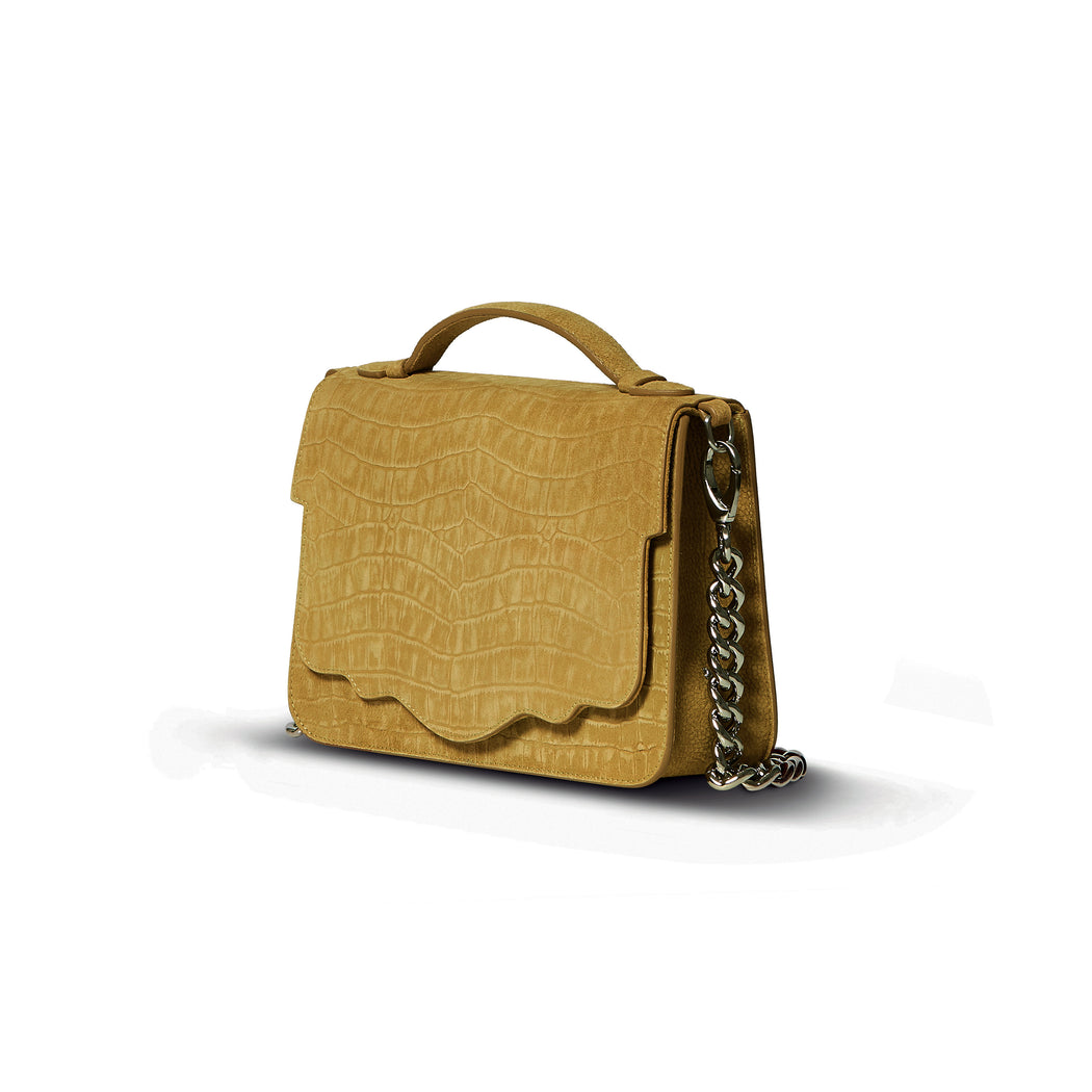 This best-selling top handle luxury leather bag in mustard sueded calfskin with all-over textured crocodile print features both a detachable crossbody leather strap and a detachable chain strap. Make it your own with a fur Duma Hok-Pom or our signature leather tassel or opt for one of our leather guitar straps for an on-trend look. It is one of the easiest to accessorize handbags.