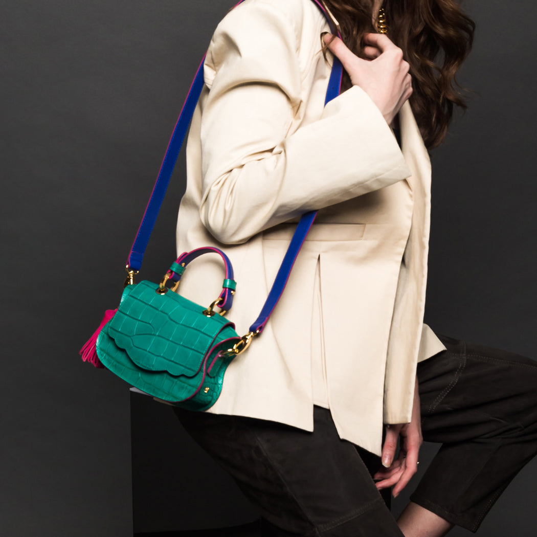 Woman carrying designer shoulder bag made of green croc-embossed leather