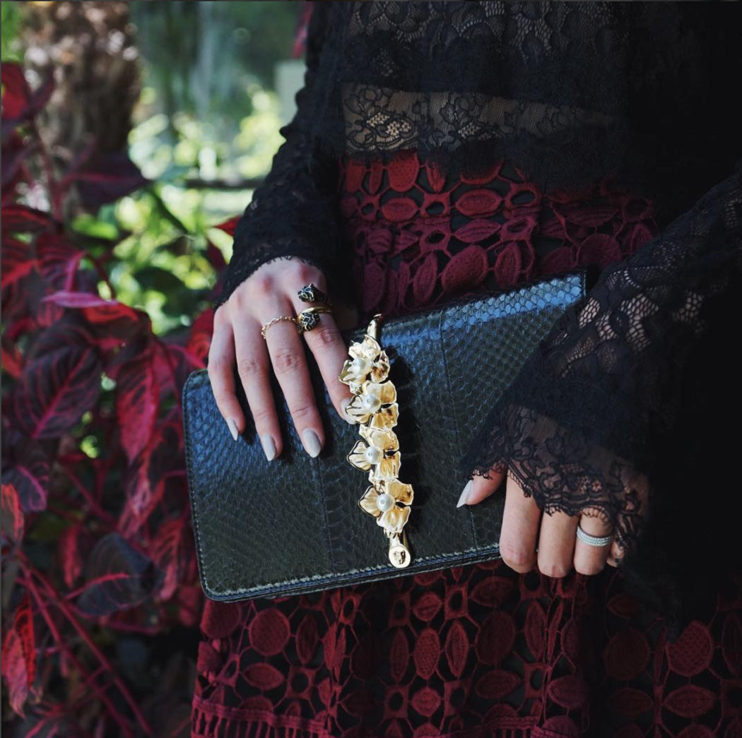 Woman's hands holding a designer evening clutch in black snakeskin